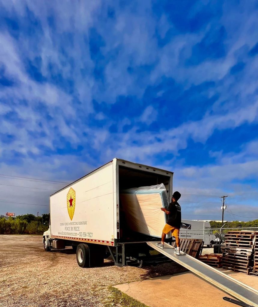 Elite Star Movers crew member loading a wrapped mattress up the ramp into the company truck